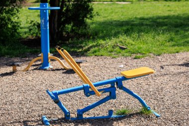 Parkın içinde tahterevalli ve hortumlu açık hava egzersiz ekipmanları.
