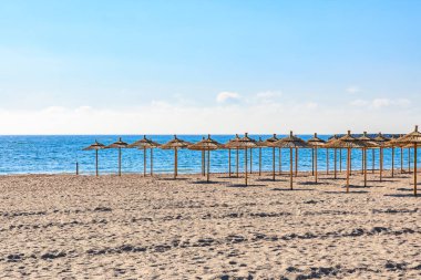 Güneşli bir günde hasır şemsiyeli boş plaj.