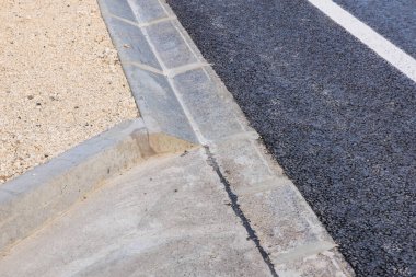 Yeni inşa edilmiş asfalt yol ve taş kaldırıma yakın çekim.