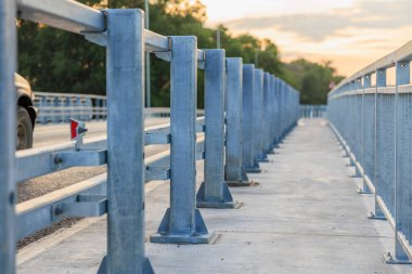 Metal parmaklıkları ve günbatımı arkaplanı olan boş şehir köprüsü.