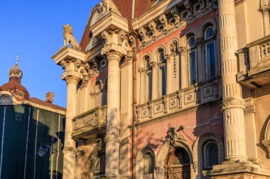 Süslü sütunlar ve gün batımında dekoratif ayrıntılarla tarihi Avrupa mimari cephesi.