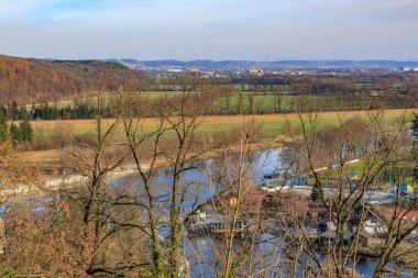 Açık bir günde kayan tepeler ve uzak kasabalarla manzaralı nehir manzarası.