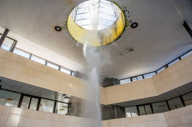 Terk edilmiş binanın modern avlusunda dairesel açıklıklı çatı penceresi çeşmesi, doğal gayzer..
