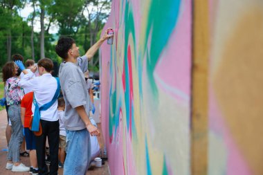 Genç Asyalı erkek açık havada renkli sokak resimleri çiziyor. 31 Mayıs 2024 Balti Moldova.