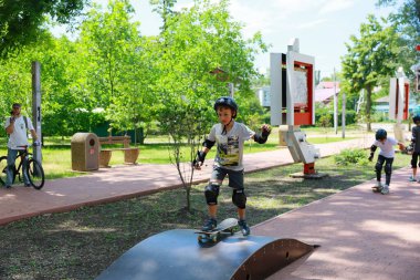 Güneşli bir günde parkta kaykay yapan beyaz çocuklar. 31 Mayıs 2024 Balti Moldova.