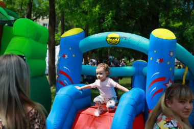 Beyaz bir çocuk açık hava parkında şişme evde eğleniyor. 31 Mayıs 2024 Balti Moldova.