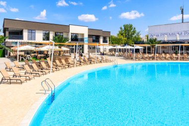 Etrafında bir sürü sandalye ve şemsiye olan bir havuz. Havuz mavi ve sandalyeler bronzlaşmış. 8 Haziran 2024 Balti Moldova