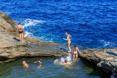 Bir grup insan havuzda yüzüyor. Su mavi ve insanlar suyun içindeler. 6 Ağustos 2024 Giola Thassos Yunanistan.