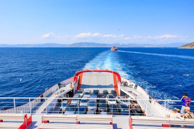 Kırmızı kapaklı bir tekne denizde yüzüyor. Tekne araba ve insanlarla dolu. 5 Ağustos 2024 Keramoti 'den Yunanistan' a feribot