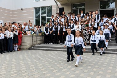 Geleneksel üniformalı çocuklar ve yetişkinlerle okul seremonisi binadan çıkıyor. 2 Eylül 2024 Balti Moldova.