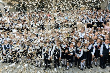 Okul çocukları konfetiyle kutlama yapıyor: bir grup genç öğrenci şenlikli anın tadını çıkarıyor. 2 Eylül 2024 Balti Moldova.