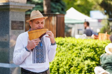 Geleneksel kıyafetlerle dışarıda pan flütü çalan yaşlı beyaz bir erkek. 22 Mayıs 2025 Balti Moldova.