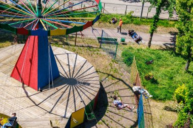 Terk edilmiş renkli dönme dolap. İnsanlar yakınlarda dinlenirken. 22 Mayıs 2025 Balti Moldova.