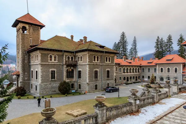 Kırmızı çatılı ve saat kulesi olan büyük bir bina. 15 Aralık 2024 Busteni Romanya.