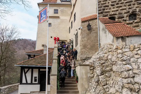 Bir grup insan binanın önündeki taş bir merdivende dikiliyorlar. 16 Aralık 2024 Bran Romanya.