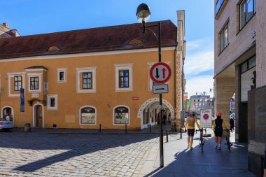 Güneşli bir günde bisikletçiler ve yayaların olduğu tarihi Avrupa sokak sahnesi. 21 Mart 2025, Ceske Budejovice, Çek.