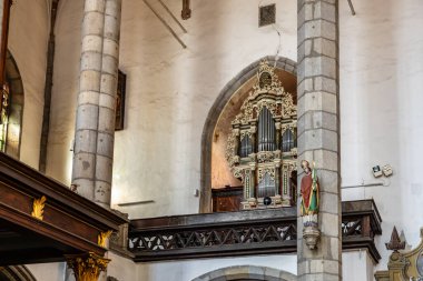 Tarihi kilise içinde boru orgu ve aziz heykeli var. 20 Mart 2025, Cesky Krumlov, Çek.