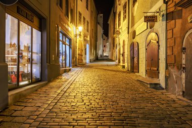 Sıcak ışıklandırmalı tarihi Avrupa kaldırım taşı sokağının atmosferik gece manzarası. 20 Mart 2025, Cesky Krumlov, Çek.