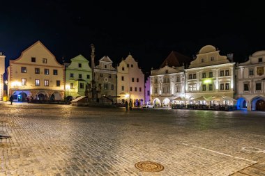 Aydınlatılmış binaları ve kaldırımlı caddeleri olan tarihi kasaba meydanının gece manzarası. 20 Mart 2025, Cesky Krumlov, Çek.