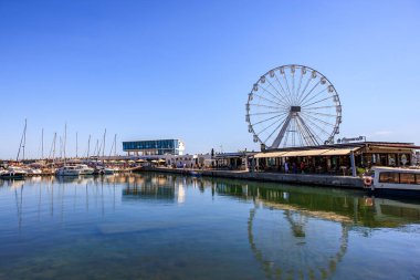 Güneşli bir günde dönme dolabı ve marinası olan deniz manzaralı bir yer. 3 Mayıs 2025 Romanya.