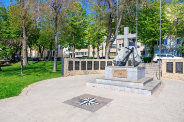 Sunny Park 'ta çapalı ve haçlı bir anıt. Ağaçlar ve taş plaklarla döşenmiş. 3 Mayıs 2025 Romanya.