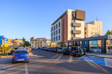 Akşam ışığında arabaları ve ticari binaları olan modern şehir caddesi. 3 Mayıs 2025 Romanya.