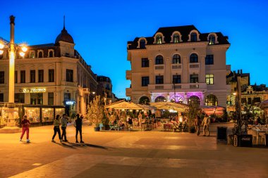 Kafeler ve tarihi mimari ile dolu hareketli bir şehir meydanı. 3 Mayıs 2025 Romanya.