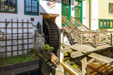 Su çarkı ve bankı olan ahşap bir yapı. Yedek kulübesi boş. Su çarkı eski ve paslı. 21 Mart 2025, Cesky Krumlov, Çek.