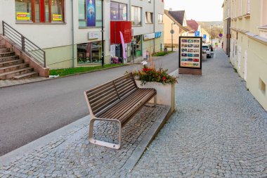 Avrupa 'nın sakin kentsel manzarasında, kaldırım taşı caddesindeki boş ahşap bank. 21 Mart 2025, Hluboka Şatosu, Çek.