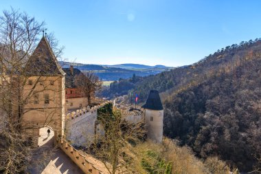 Ortaçağ şatosu açık mavi gökyüzünün altındaki orman tepeleriyle çevrili..