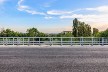 Bereketli yeşillik ve gün batımında berrak gökyüzü olan manzaralı şehir köprüsü.