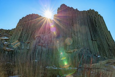 Çek topraklarında Panska Skala 'daki görkemli bazalt sütunların üzerine güneş ışığı vuruyor.
