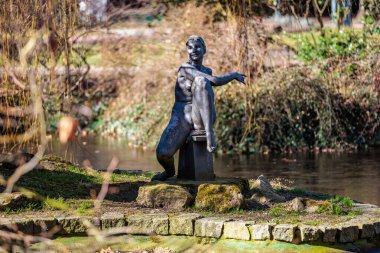 Park ortamında oturan kadın figürünün bronz heykeli. 19 Mart 2025, Karlovy Vary, Çek Cumhuriyeti.