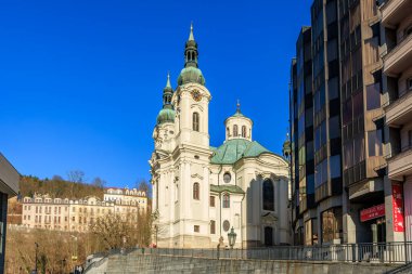 Avrupa 'da berrak mavi gökyüzüne karşı çarpıcı barok kilise mimarisi. 18 Mart 2025, Karlovy Vary, Çek Cumhuriyeti.