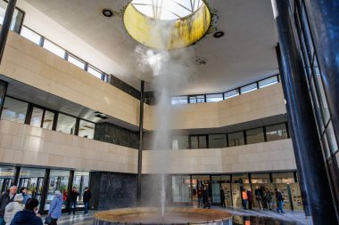 Modern atriyumdaki kapalı havuzda ziyaretçiler su gösterisini izliyor. 18 Mart 2025, Karlovy Vary, Çek Cumhuriyeti.