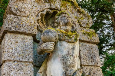 Yosun kaplı taş heykel yemyeşil ormanda. 17 Mart 2025, Konopiste Şatosu, Çek Cumhuriyeti.