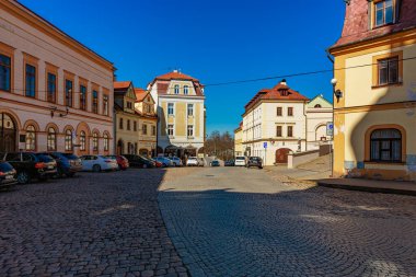 Tarihi binaları ve kaldırım taşı sokağıyla güneşli Avrupa meydanı. 18 Mart 2025, Madalyon, Çek Cumhuriyeti.