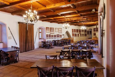 Historic dining hall with wooden ceiling and chandeliers in medieval castle. March 18, 2025, Loket, Czech Republic.