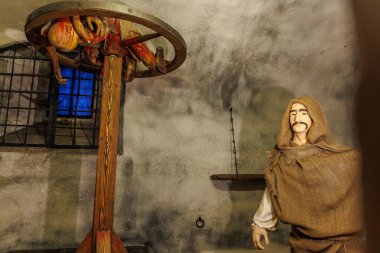 Medieval torture exhibit with rack and hooded figure in dimly lit setting. March 18, 2025, Loket, Czech Republic.