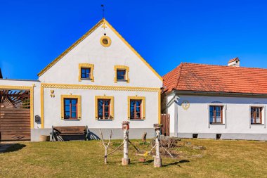 Charming rural european houses with red roofs and yellow accents under clear blue sky. March 21, 2025, Holasovice, Czechia.