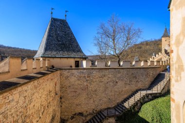 Medieval castle walls and towers on sunny day with blue sky in scenic landscape. March 19, 2025, Karlstejn, Czech Republic.