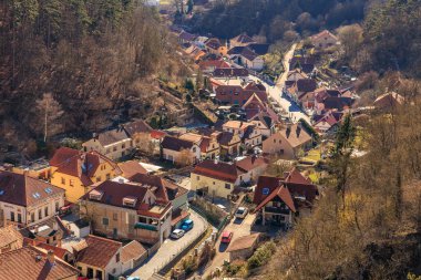 Scenic hilltop view of quaint european village with red roofs and forest surroundings. March 19, 2025, Karlstejn, Czech Republic.