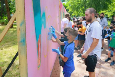 Young artists creating vibrant outdoor mural with spray paint. May 31, 2024 Balti Moldova.