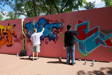 Young men creating colorful graffiti art on outdoor walls. May 31, 2024 Balti Moldova.