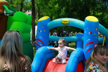 Caucasian child on colorful inflatable slide in outdoor park event. May 31, 2024 Balti Moldova.