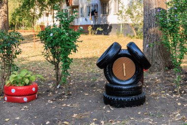 Creative tire garden decor with plants and recycled clock in outdoor setting. July 17, 2024 Balti Moldova.