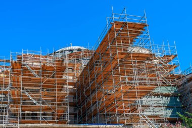 Scaffolding surrounds historic building under renovation with clear blue sky.