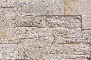 Rustic beige stone wall texture with horizontal brick pattern.