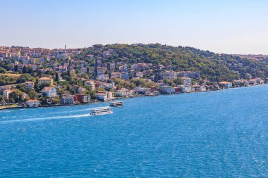 Scenic view of bosphorus strait with boats and hillside architecture.