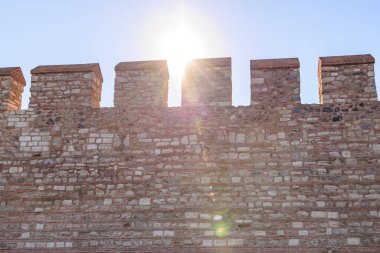 Sunlight shining over historic stone fortress wall battlements.